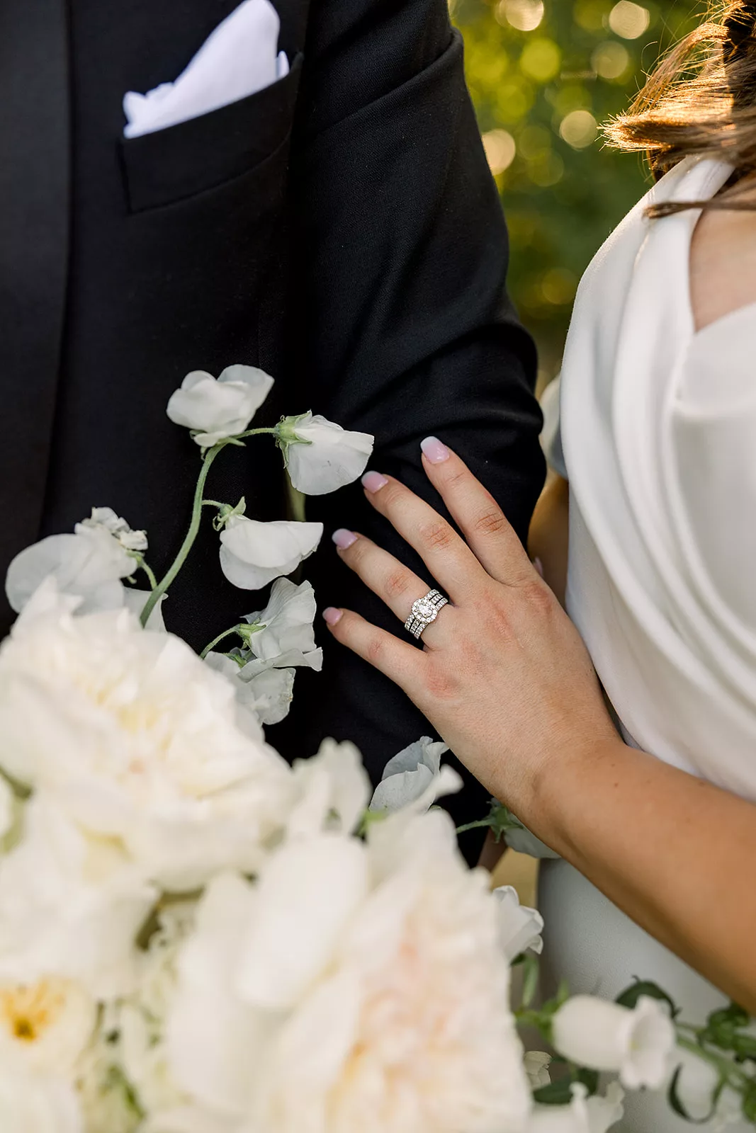 Details of a bride's ring hand holding her groom's arm
