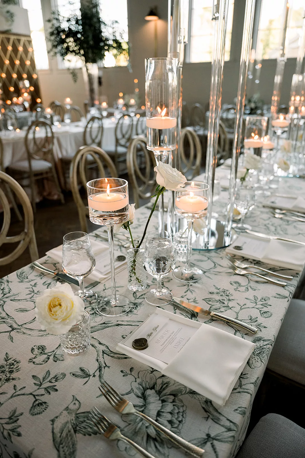 Details of a long table set up for a wedding reception with white roses