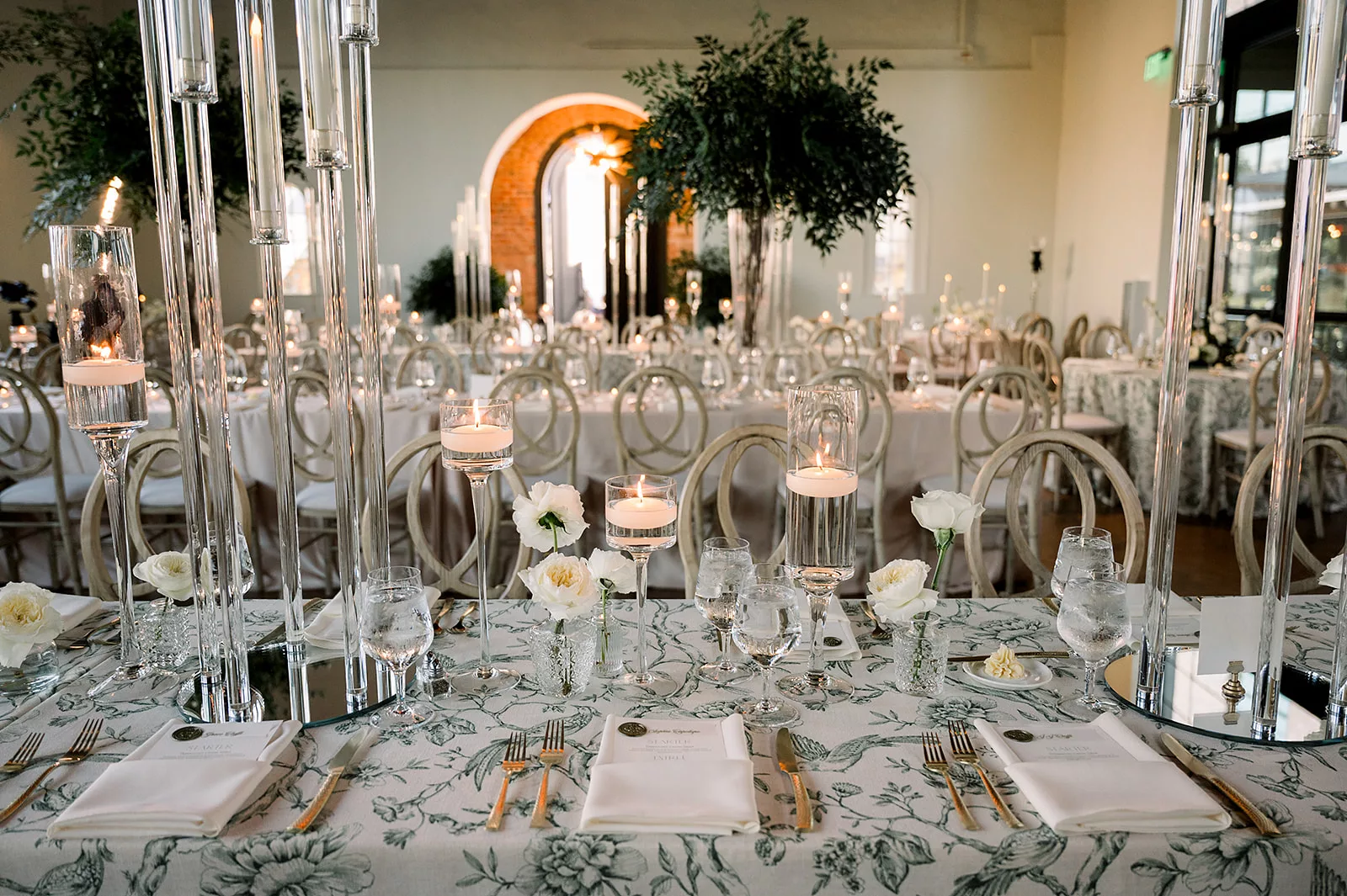 Details of a wedding reception table set up with gold silverware and floral linens