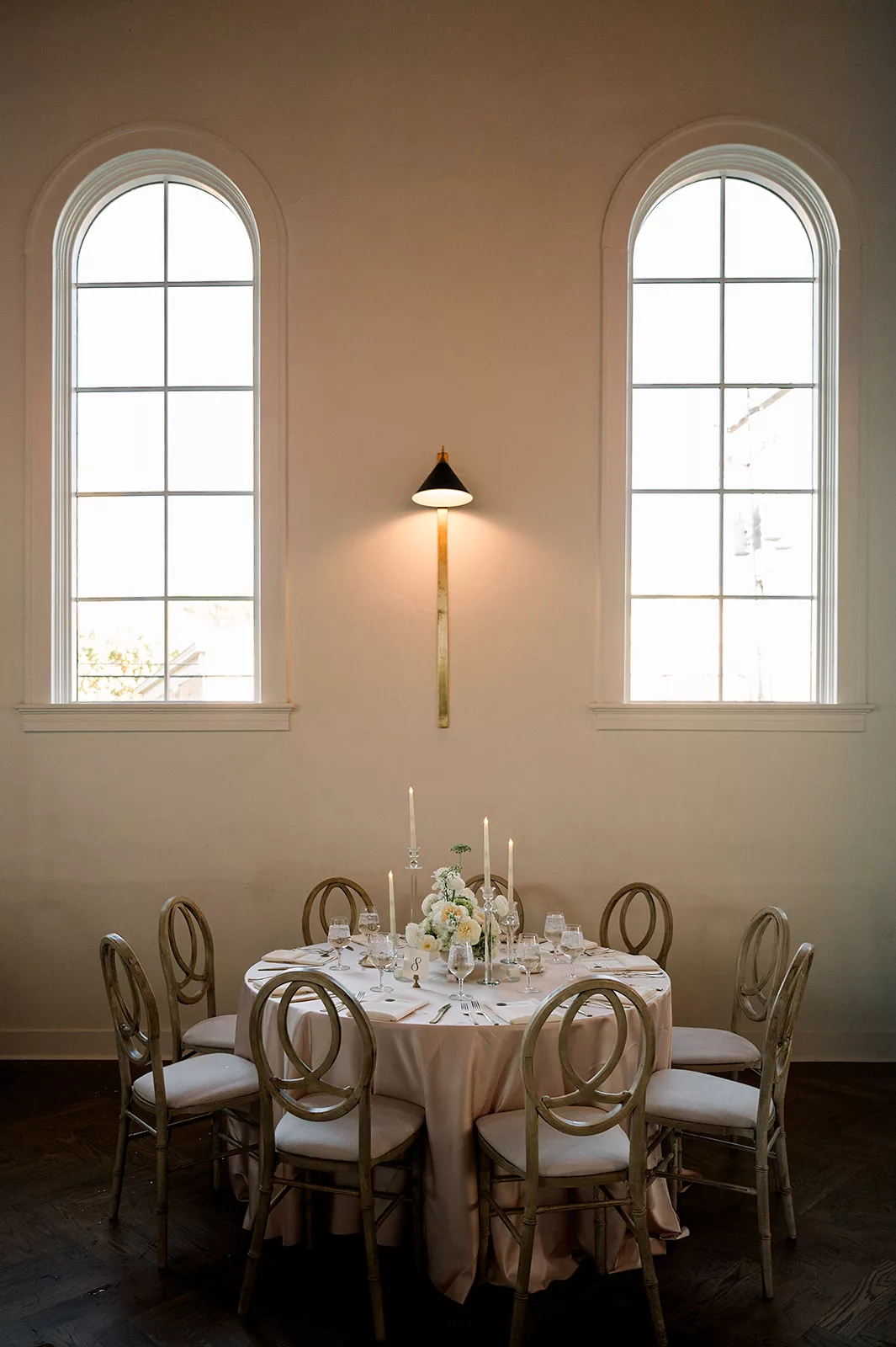 Details of a round wedding reception table set up under two large windows