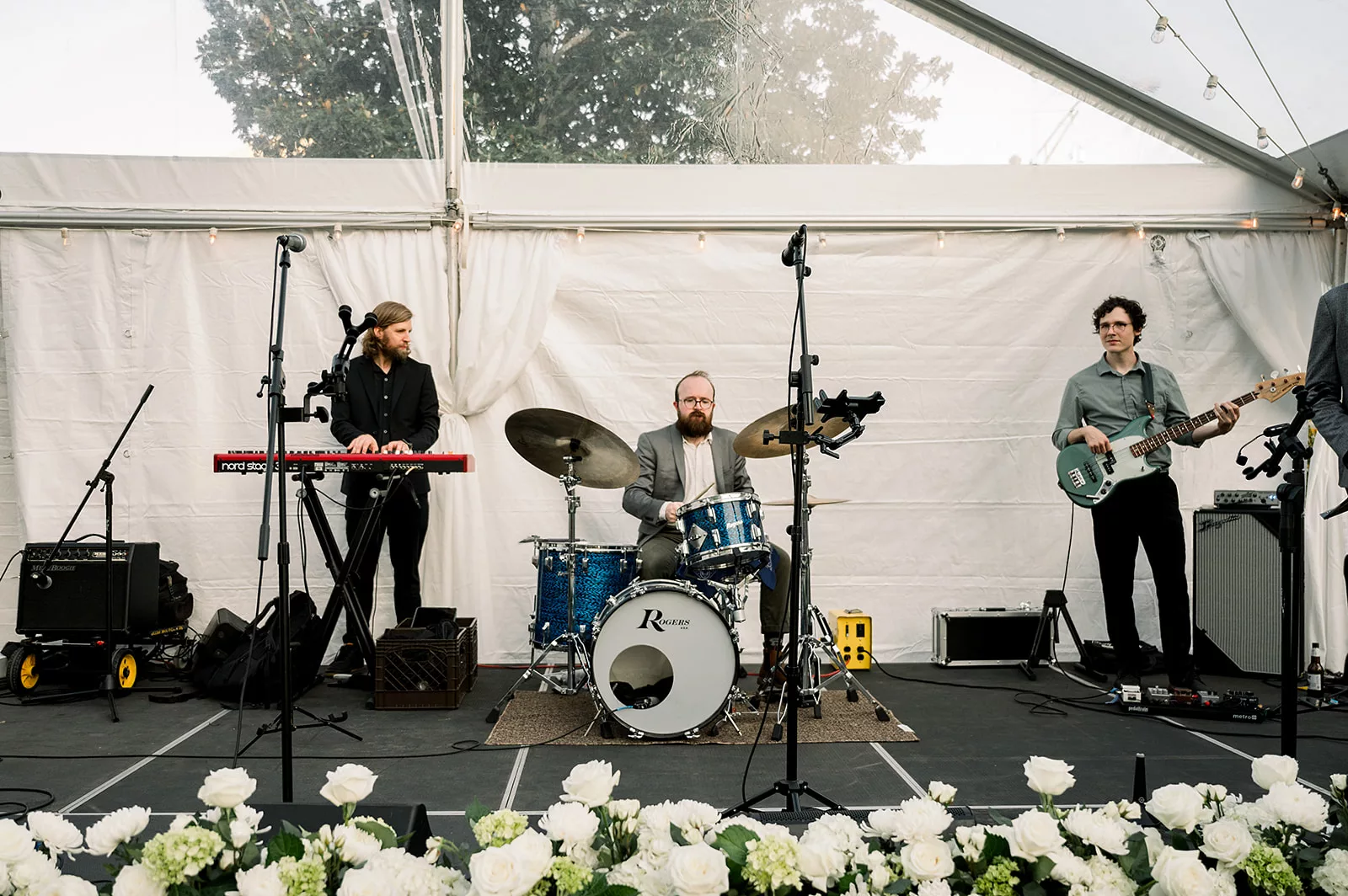 A band plays live for a wedding reception under a clear tent