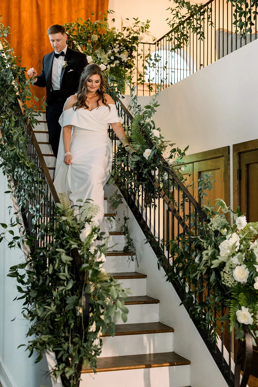 Newlyweds walk down a flower lined set of stairs at The Chapel Athens