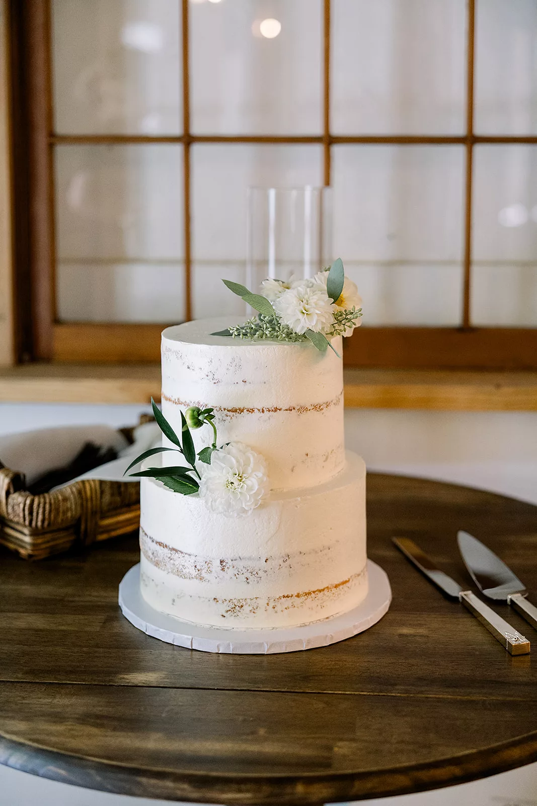 Details of a white two tier cake sitting on a wooden table
