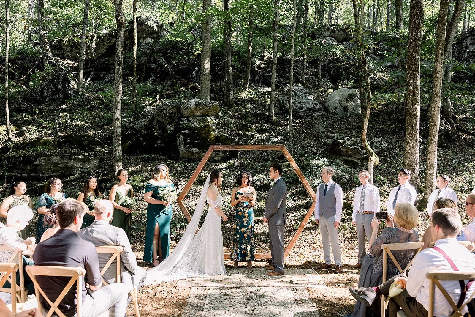 Newlyweds stand under an arbor during their wedding ceremony in the woods