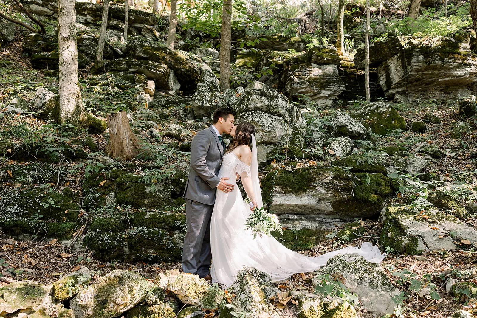 Newlyweds kiss in a rocky mountain forest at their Sustainable Wedding Venue