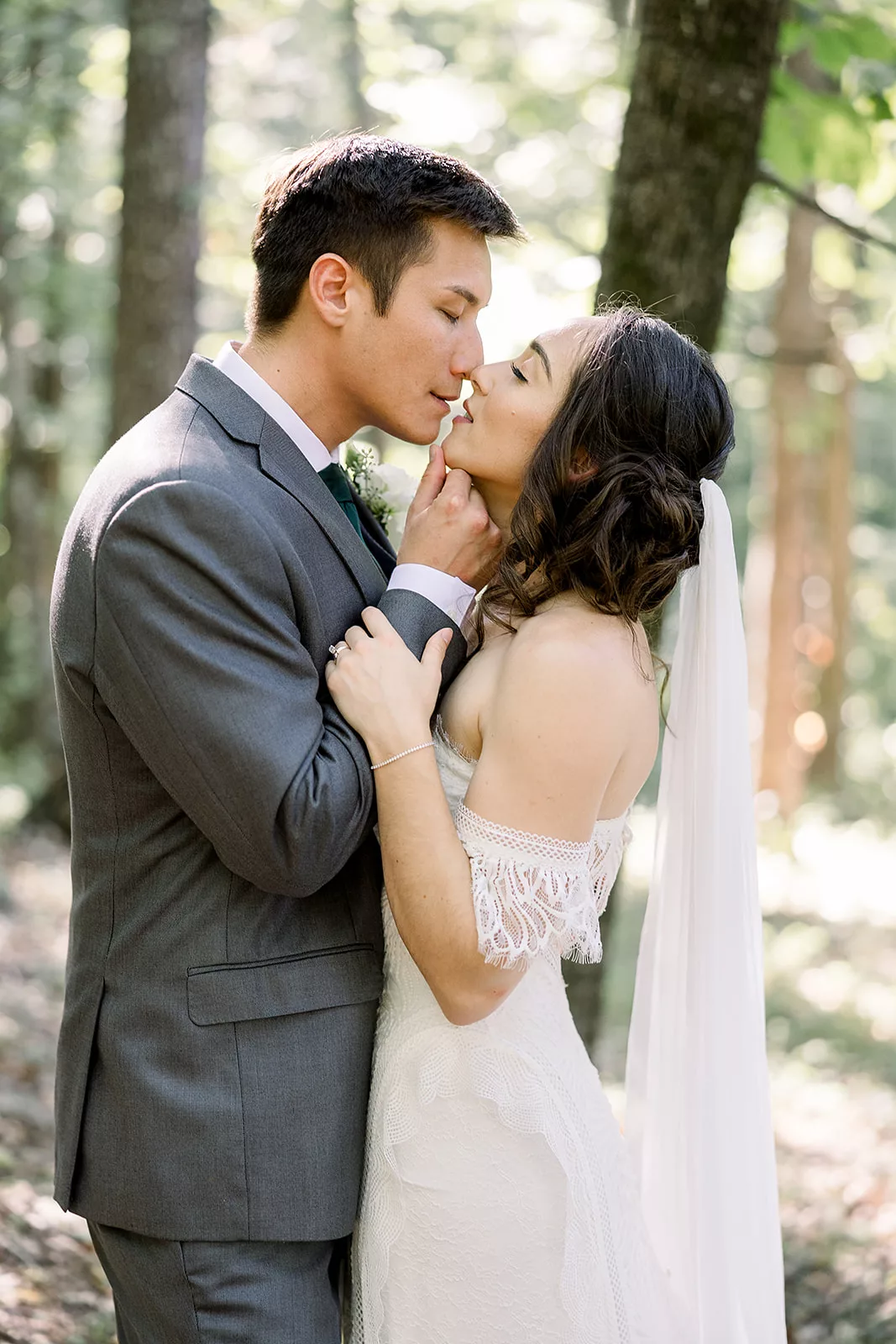 Newlyweds lean in for a kiss while standing in a forest at one of the Sustainable Wedding Venue