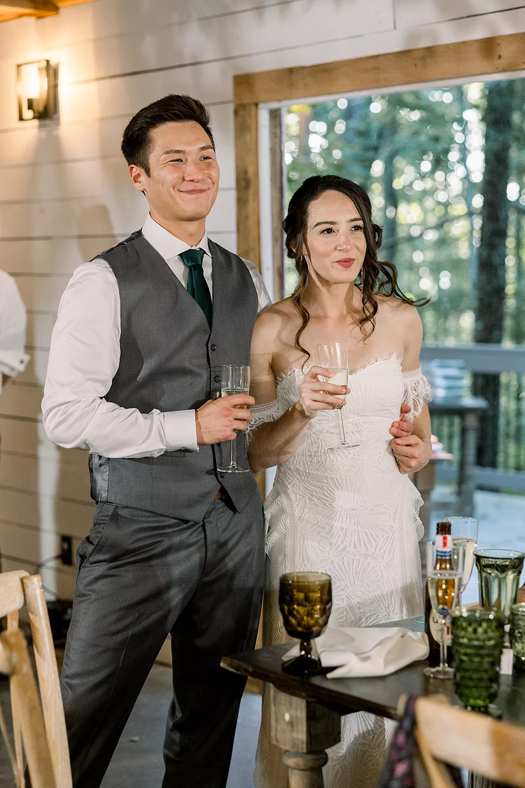 Newlyweds stand together at their reception holding champagne glasses