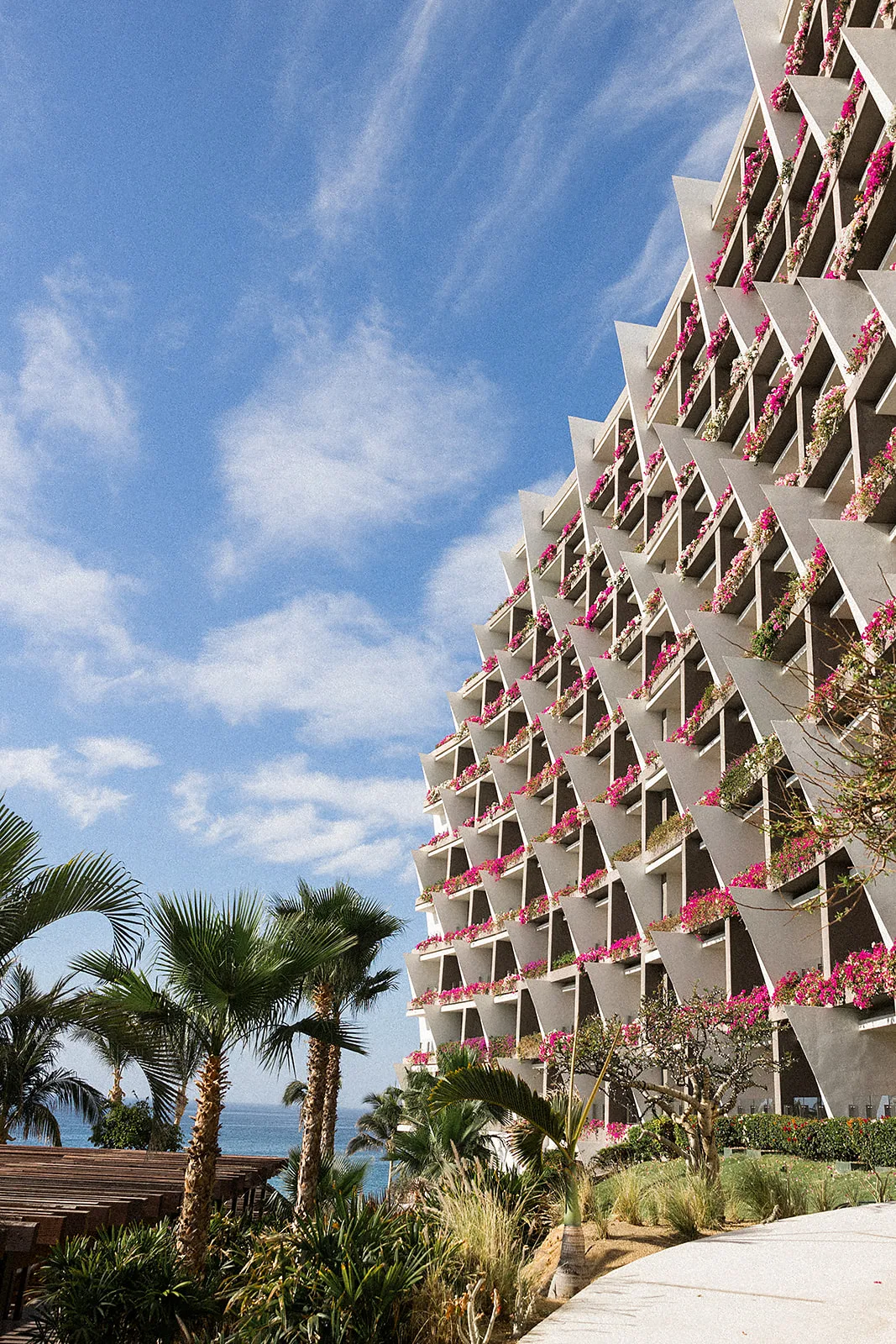 A look up at the Grand Velas Los Cabos Wedding venue with bright pink flowers in each balcony